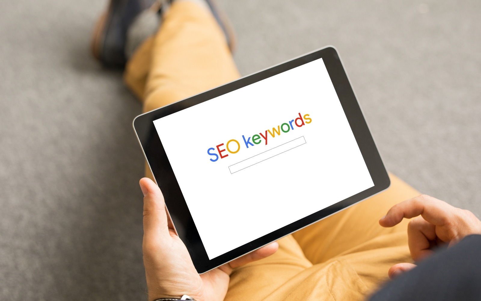 Person holding a tablet displaying an SEO keywords search interface, representing B2B keyword research and search intent strategy