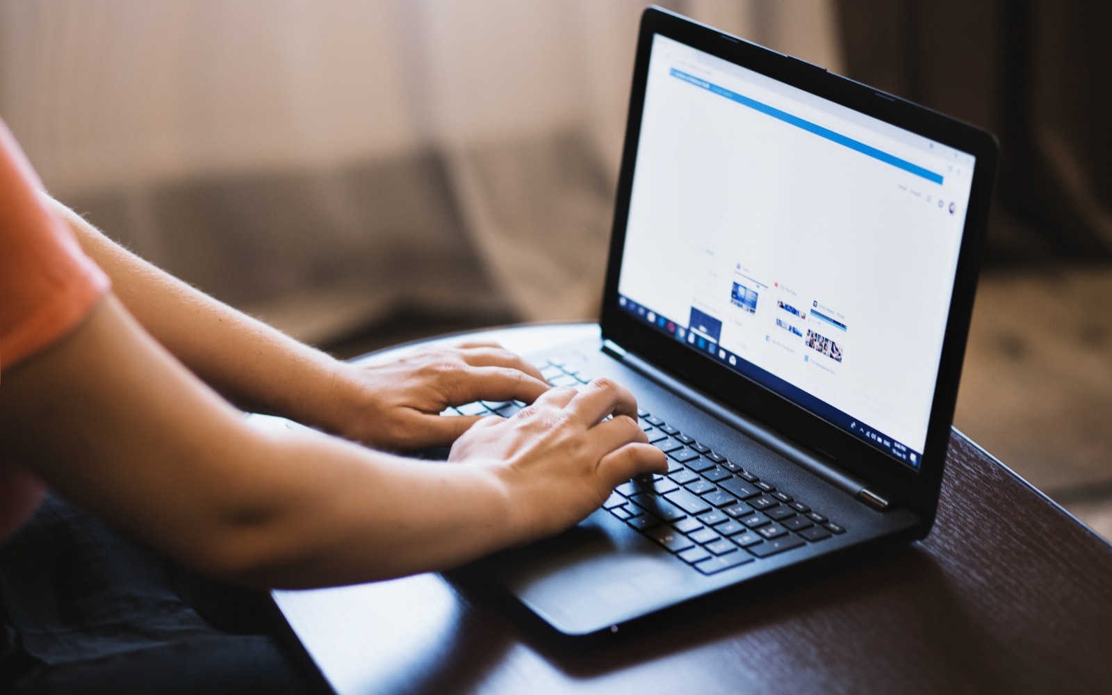 Person browsing an ecommerce or product listing website on a laptop, hands on keyboard in a casual home setting